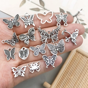 Vintage silver butterfly charm assortment for DIY jewelry making in a hand palm