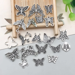 Detailed view of antique silver butterfly charms for DIY jewelry making on a tray