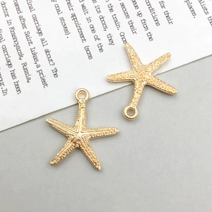 Détails de deux breloques étoiles de mer dorées avec texture grainée et anneau d'attache