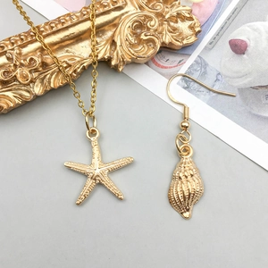 Gros plan de pendentifs dorés en forme d'étoile de mer et de conque au design élégant