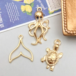 Gros plan de pendentifs animaux marins en or KC avec pieuvre, queue de baleine et tortue