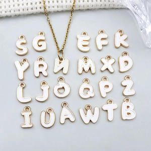 Makroansicht weißer Emaille-Alphabet-Anhänger mit vergoldeten Gliedern für Schmuck