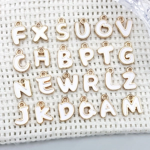 Draufsicht auf A-Z Buchstabenanhänger aus Goldlegierung mit weißer Emaille für DIY-Schmuck