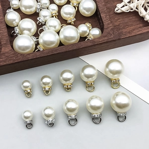 Detalle de colgantes de perlas con tapas de metal y strass en tonos oro y plata