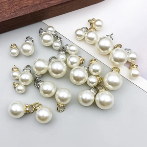 Detalle macro de colgantes de perlas con pedrería en monturas de oro y plata