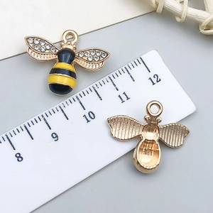 Detail of bee charm showing enamel finish, rhinestones and size on ruler scale
