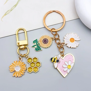 Detailed macro view of daisy, honeycomb, and bee enamel charms on golden keychains