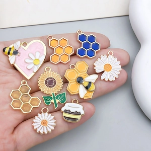 Colorful enamel bee and honeycomb charms set for DIY jewelry making shown in hand