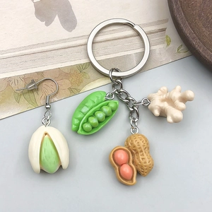 Detailed view of realistic resin pea pod, ginger and peanut charms on a silver keychain