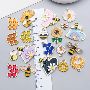 Mix of 20 colorful enamel bee and flower alloy pendants displayed with a measurement ruler