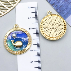 Detail of 30mm round alloy ocean pendant with gold whale design and pearl border