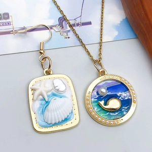 Detail of whale pendant and starfish earring with resin ocean theme and faux pearls