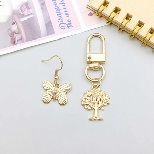 Golden butterfly earrings and tree of life keychain with detailed metal engravings