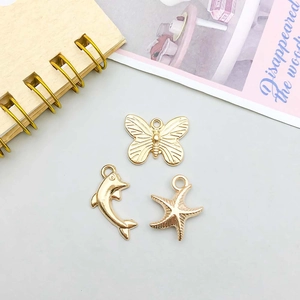 Detailed close-up of golden dolphin butterfly and starfish charms for DIY jewelry making
