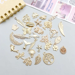 Detailed arrangement of various gold alloy pendants including butterflies and feathers for DIY