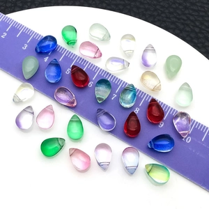 Colorful teardrop glass charms for DIY jewelry making displayed on a white plate