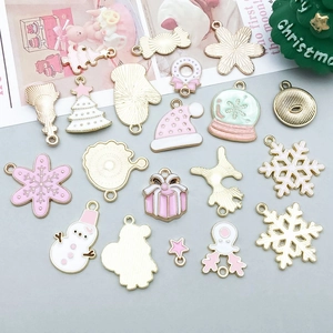 Flat lay of pink and gold enamel Christmas charms like snowflakes and Santa trees