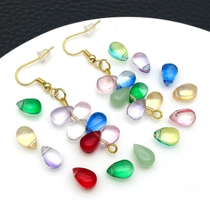 Macro shot of colorful glass water drop pendants in various vibrant shades on a white tray