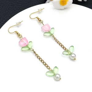 Detalle de pendientes de tulipán de cristal rosa con cadena dorada y perla blanca