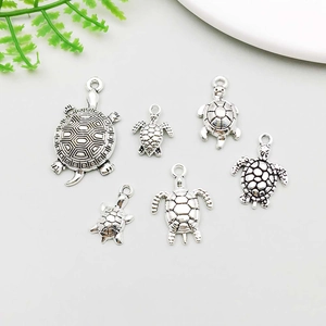 Macro shot of six antique silver turtle pendants with detailed shell patterns and loops