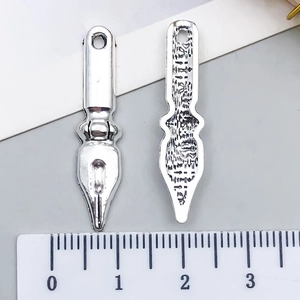 Vue macro de deux breloques plume en argent vintage montrant une longueur de 3,2 cm
