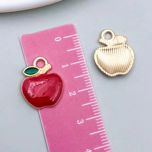 Détail des breloques pomme en émail rouge avec dos en métal doré et dimensions