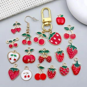 Vue détaillée de divers pendentifs en émail rouge aux motifs de fraise et cerise pour DIY