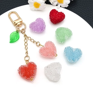 Macro detail of frosted acrylic heart charms with sugary texture and gold clasp chain