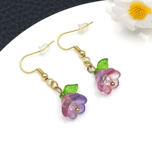 Detail of translucent purple and pink gradient lily of the valley earrings with green leaves