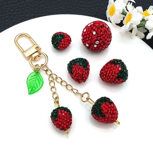 Macro shot of sparkling red rhinestone strawberry charms with gold lobster clasp