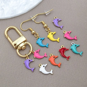 Detailed view of colorful enamel dolphin charms and golden jewelry accessories on gray fabric