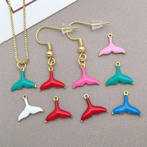 Detailed set of colorful enamel mermaid tail charms and gold necklaces on textured fabric