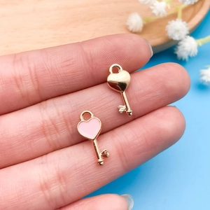 Gedetailleerde weergave van kleine hartsluiting hangers in roze email en goud