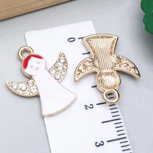 Detail of angel pendant with white enamel and crystals on a measuring scale board