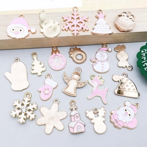 Detailed close-up of pink and white enamel Christmas charms on a natural wood surface