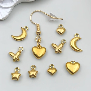 Detalle de dijes de acero inoxidable dorado con formas de corazón, mariposa y luna