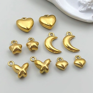 Detalle de colgantes dorados de acero inoxidable con corazones y mariposas para bisutería