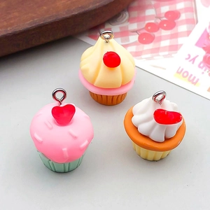 Détail de trois pendentifs cupcake en résine colorée avec cœurs et anneaux métalliques