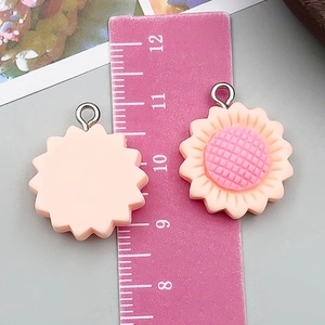Detail of pink resin sunflower charms with metal ring and ruler for size measurement