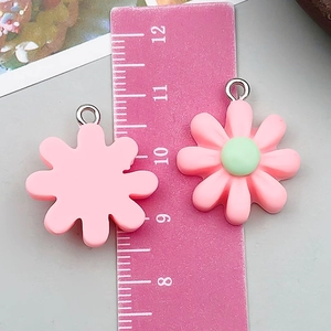 Pink resin sunflower charms for DIY jewelry making shown with size measuring ruler