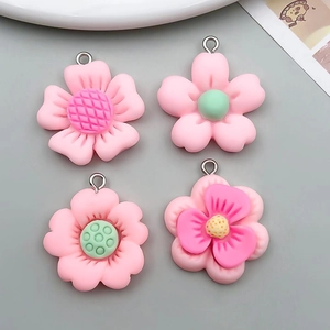 Close-up of four pink resin flower charms with detailed centers and metal rings