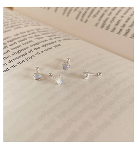 Detalle de pendientes de plata 925 con piedra de luna sobre páginas de un libro