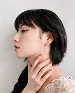 Detalle de pendientes de borla plateados y anillo con pedrería en modelo con luz suave