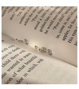 Primer plano de pendientes de plata 925 y piedra de luna sobre páginas de libros