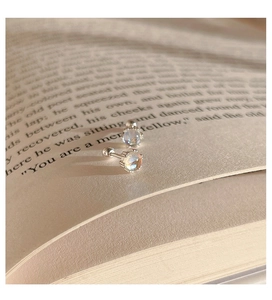 Detalle de pendientes de plata 925 con piedra de luna y cierre de rosca en un libro