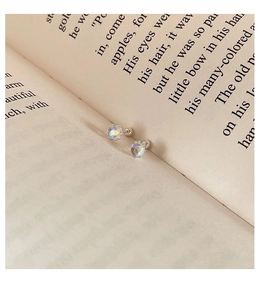 Detalle macro del pendiente de plata 925 con piedra lunar y cierre de rosca sobre libro