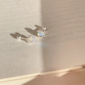 Pendientes de plata S925 con piedra de luna y cierre de rosca sobre un libro