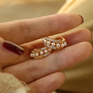 Detailed macro view of 925 silver needle hoop earrings with mini pearls and gold plating
