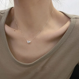 Élégant collier avec pendentif coeur en argent porté par une femme style minimaliste
