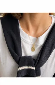 Detail der Goldkette mit quadratischem Briefumschlag-Anhänger auf einem weiblichen Modell